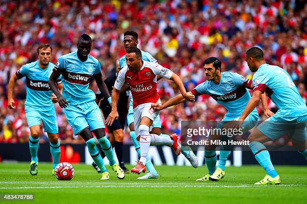 Santi Cazorla of Arsenal evades Cheikhou Kouyate and James Tomkins of West Ham United during the Barclays Premier League match between Arsenal and...
