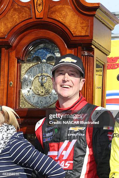 Kurt Busch, driver of the Haas Automation Chevy SS, poses for a picture with his grandfather clock trophy in victory lane after winning the STP Gas...