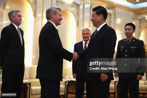 Ambassador to China Max Baucus shakes hands with Chinese President Xi Jinping as Secretary of Defense Chuck Hagel looks on during a meeting at the...