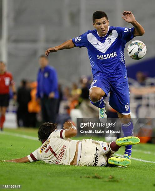 Facundo Omar Cardozo of Velez Sarsfield fights for the ball with Miguel Torres of Universitario during a match between Velez Sarsfield and...