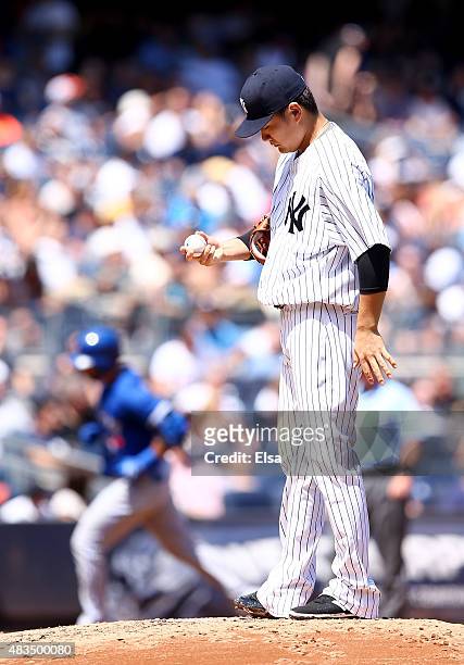 Masahiro Tanaka of the New York Yankees reacts as Jose Bautista of the Toronto Blue Jays rounds the bases after a solo home run in the fourth inning...