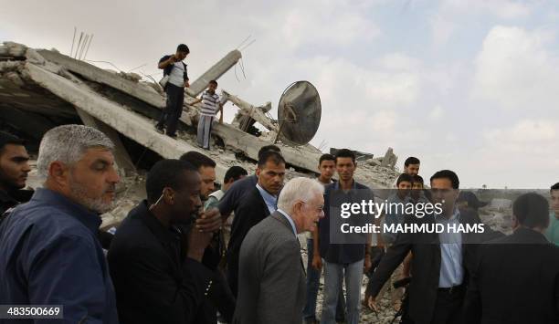 Former US President Jimmy Carter walks past the ruins of a building which was destroyed during the December-January Israeli offensive as he visits...