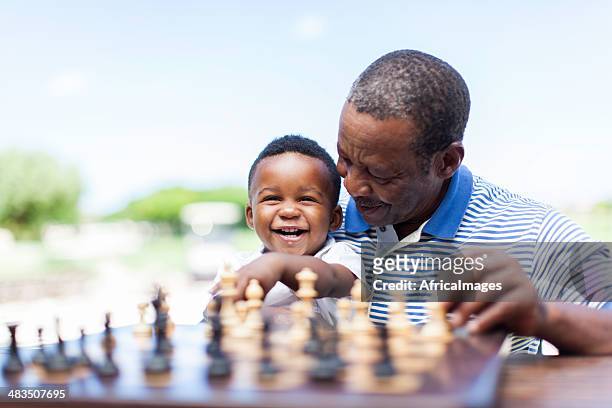 african grandfather playing chess with his grandson - kids playing chess stock pictures, royalty-free photos & images