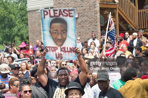 People gathered outside the Canfield Green Apartments where Michael Brown was killed listens to speakers during a memorial service marking the...