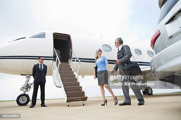 mature couple de professionnels qui voyagent en jet privé de luxe - older couple travelling photos et images de collection