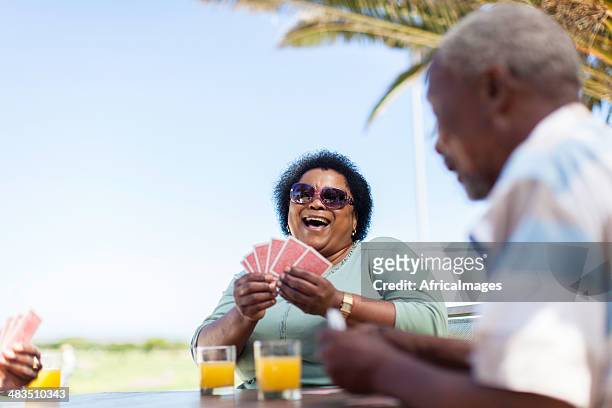 afrikanische senior frau mit einem gut lachen und spielen-karte - card game mature people stock-fotos und bilder