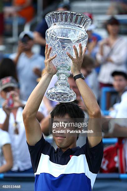 Kei Nishikori of Japan celebrates with the trophy after defeating John Isner of the United States in the men's singles final during the Citi Open at...