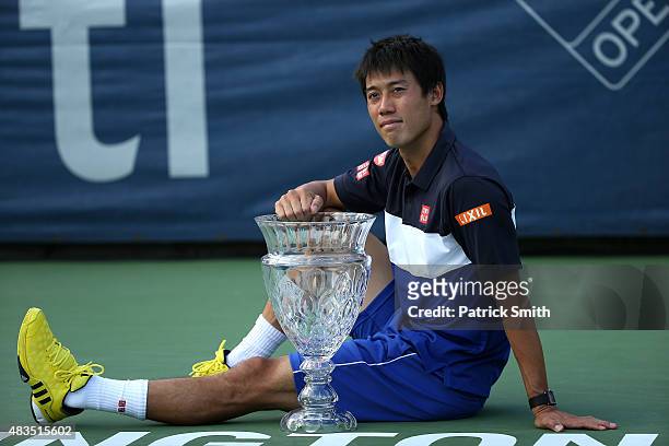 Kei Nishikori of Japan celebrates with the trophy as he poses for photographers after defeating John Isner of the United States in the men's singles...