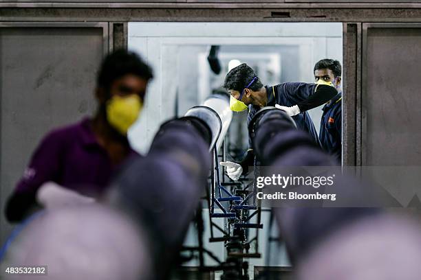 Employees clean gas tanks for the Royal Enfield Motors Ltd. Classic 350 motorcycle moving on a conveyor on the production line at the company's...