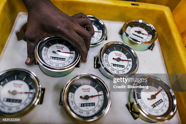 An employee picks up a speedometer for the Royal Enfield Motors Ltd. Classic 350 motorcycle on the production line at the company's manufacturing...