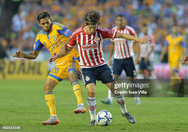 Javier Aquino of Tigres struggles for the ball with Carlos Fierro of Chivas during a 3rd round match between Tigres UANL and Chivas as part of the...