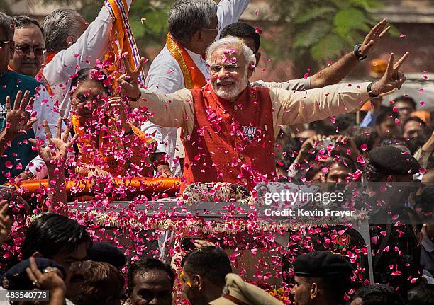 Supporters throw flower petals as Bharatiya Janata Party leader Narendra Modi rides in an open jeep on his way to file nomination papers on April 9,...