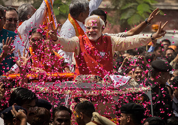 Supporters throw flower petals as Bharatiya Janata Party leader Narendra Modi rides in an open jeep on his way to file nomination papers on April 9,...