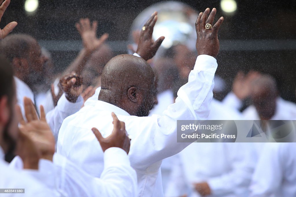 Congregants with arms raised during the spray of water. The...