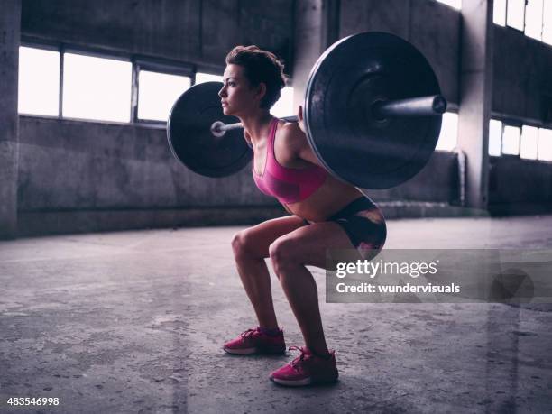 young woman resting a heavy barbell on her shoulders - youth weight training stock pictures, royalty-free photos & images