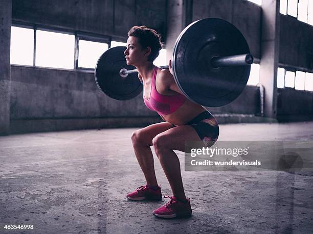 young woman resting a heavy barbell on her shoulders - daily sport girls bildbanksfoton och bilder