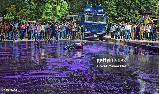 Indian police fire a jet of purple dyed chemical water from their water canon at Kashmiri government employee during a protest against the government...
