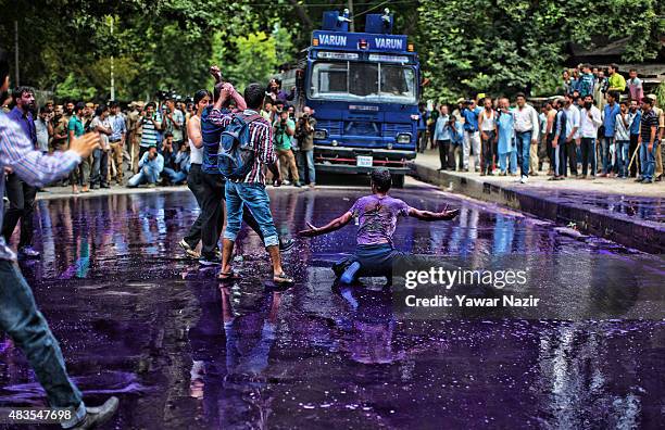 Indian police fire a jet of purple dyed chemical water from their water canon at Kashmiri government employee during a protest against the government...