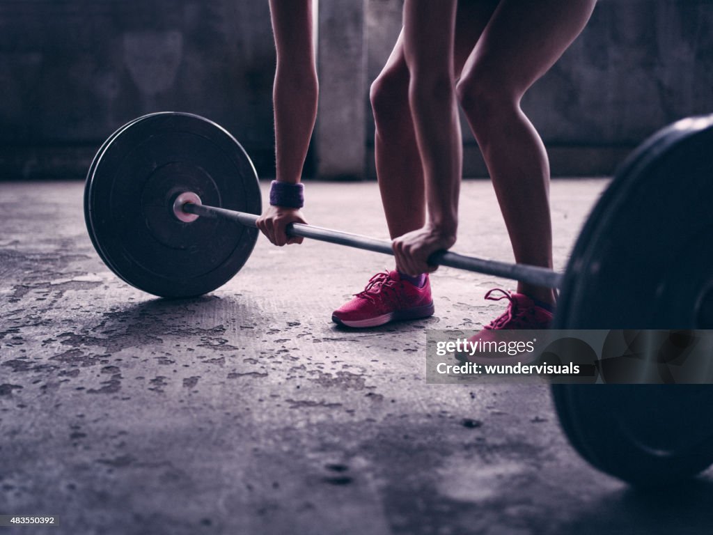 Woman gripping a barbell with heavy weights about to lift