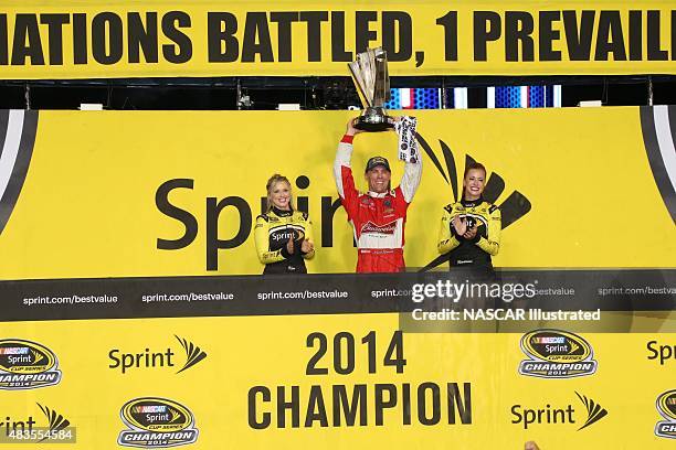 Kevin Harvick, driver of the Budweiser Chevy SS, celebrates with the trophy in victory lane after winning the NASCAR Sprint Cup Series Ford Ecoboost...
