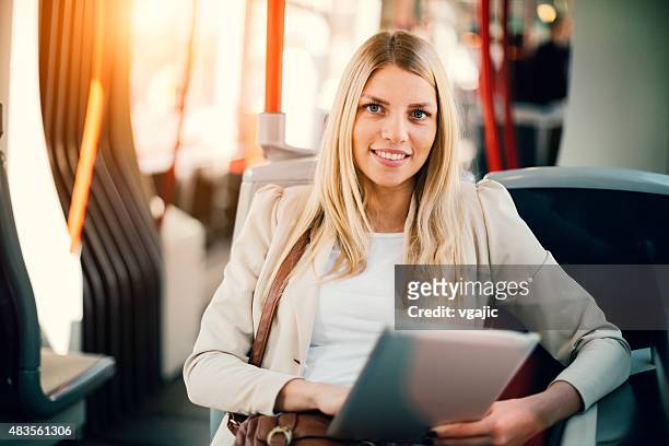 junge frau tippen auf ihrem tablet in den öffentlichen verkehrsmitteln. - bus innen stock-fotos und bilder