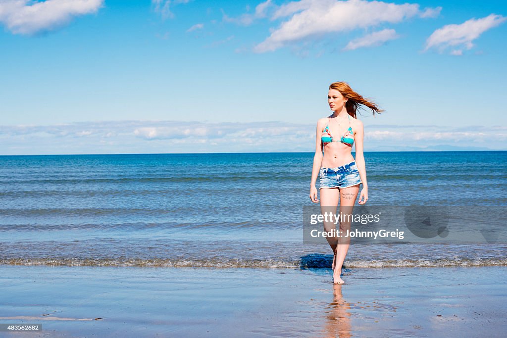 Beautiful redhead young woman walking out of the sea