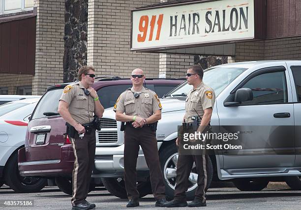 Police stand guard outside the 911 Hair Salon which was looted last night during a demonstration to mark the first anniversary of the shooting of...