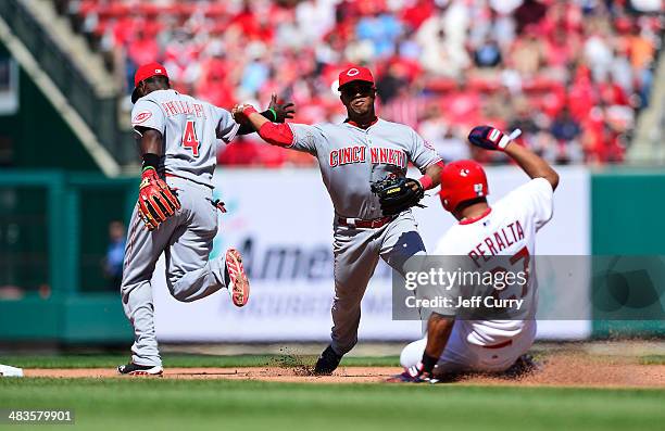 Ramon Santiago of the Cincinnati Reds turns a double play as Jhonny Peralta of the St. Louis Cardinals slides during the eighth inning at Busch...
