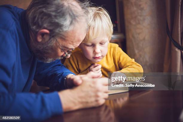 little boy reading a book with his grandpa - boy yellow shirt stock pictures, royalty-free photos & images