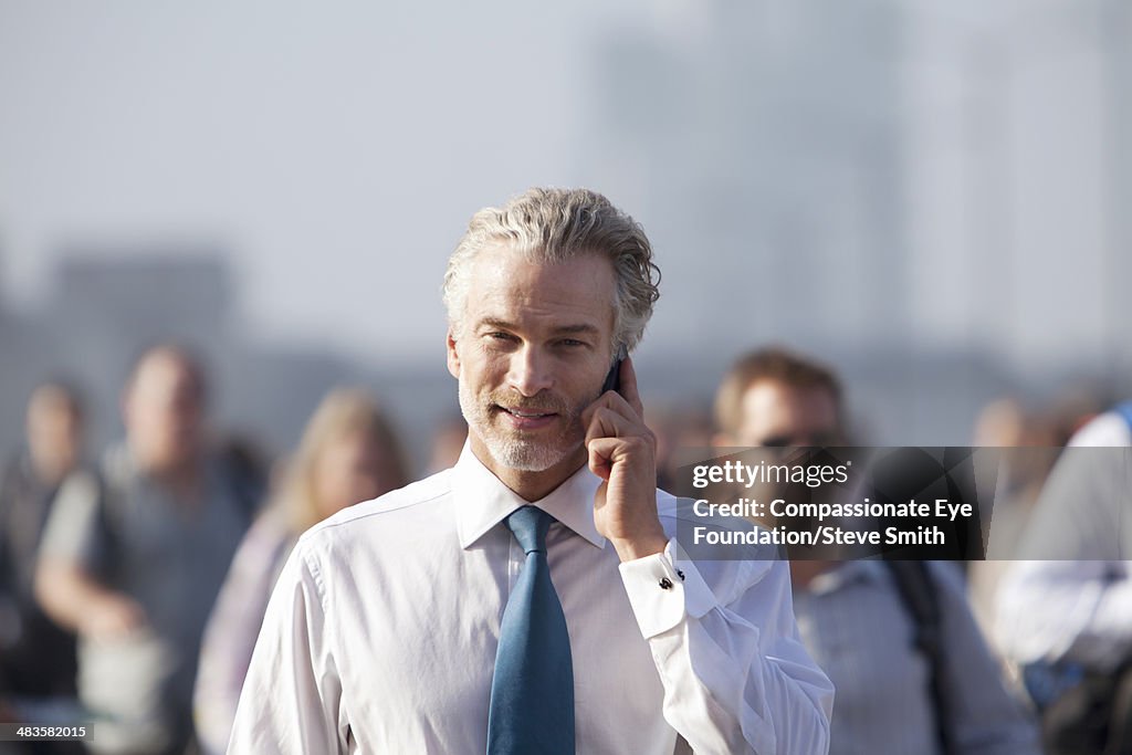 Businessman using cell phone on busy city street