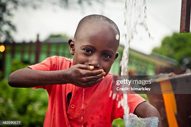 african boy by water pump - pomp stockfoto's en -beelden