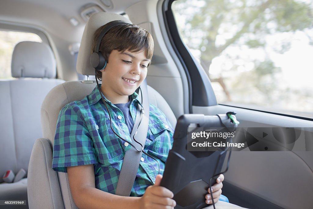 Happy boy using digital tablet in back seat of car