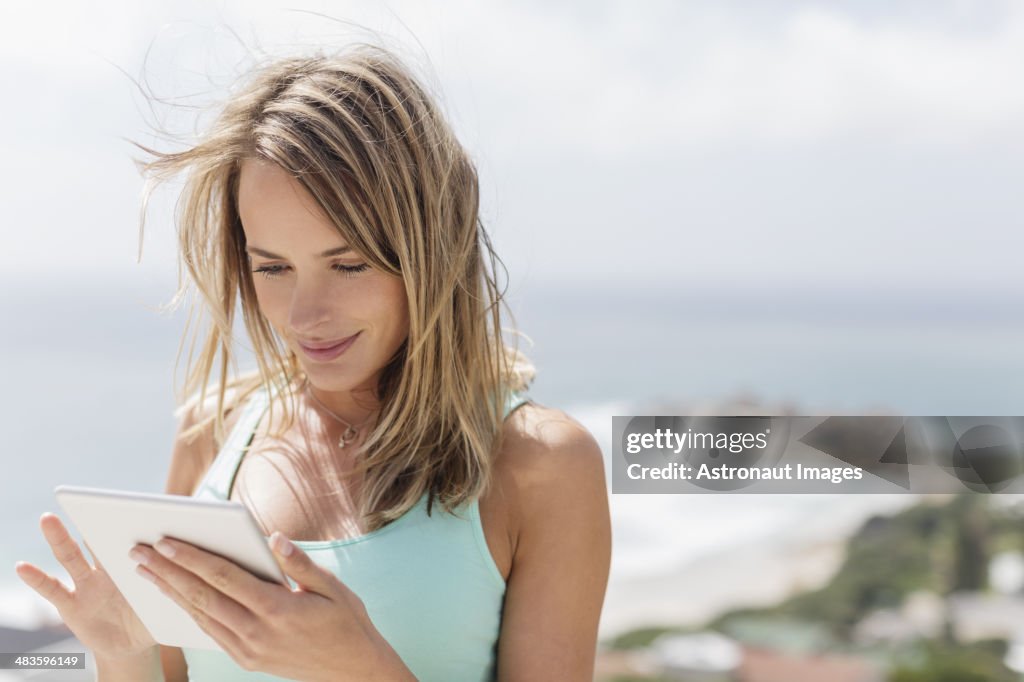 Mujer usando tableta digital con vista al mar de fondo