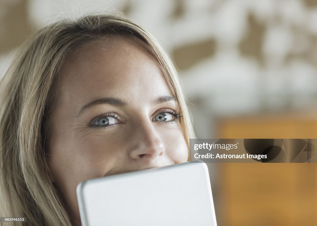 Close up portrait of woman behind digital tablet