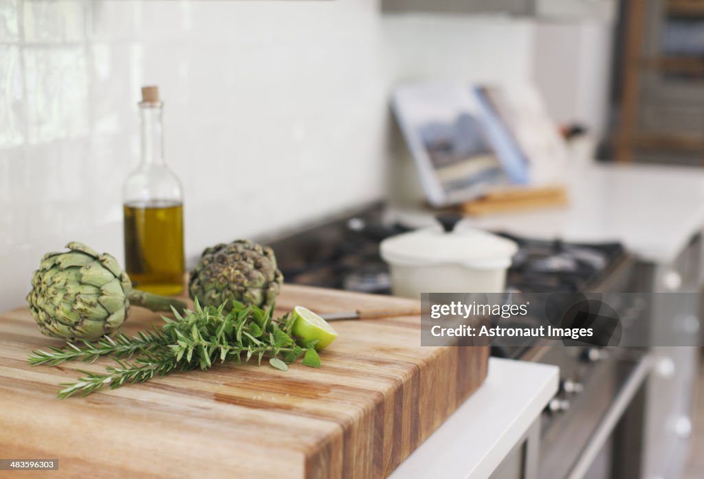 Artichokes, romero, aceite de oliva y limón sobre tabla de cortar