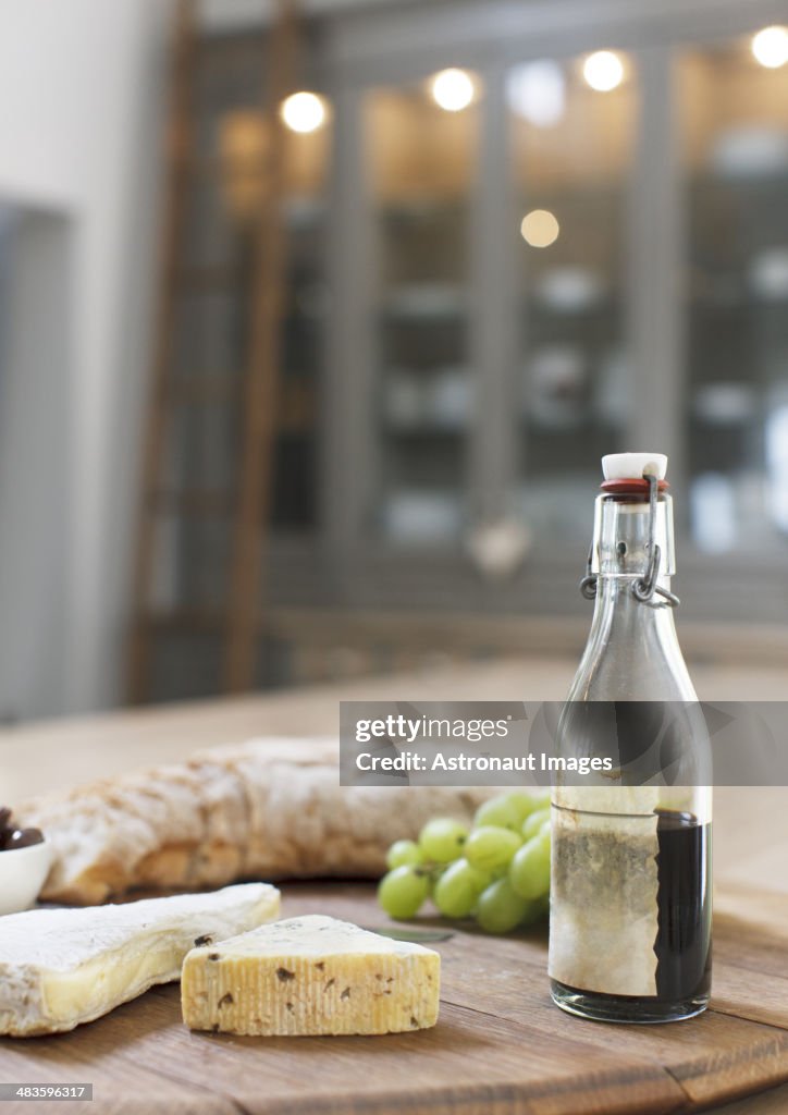 Cheese, balsamic vinegar, grapes and baguette on wooden board