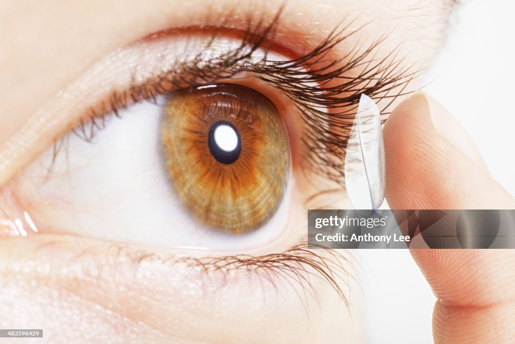 Extreme close up of girl putting contact lens in eye