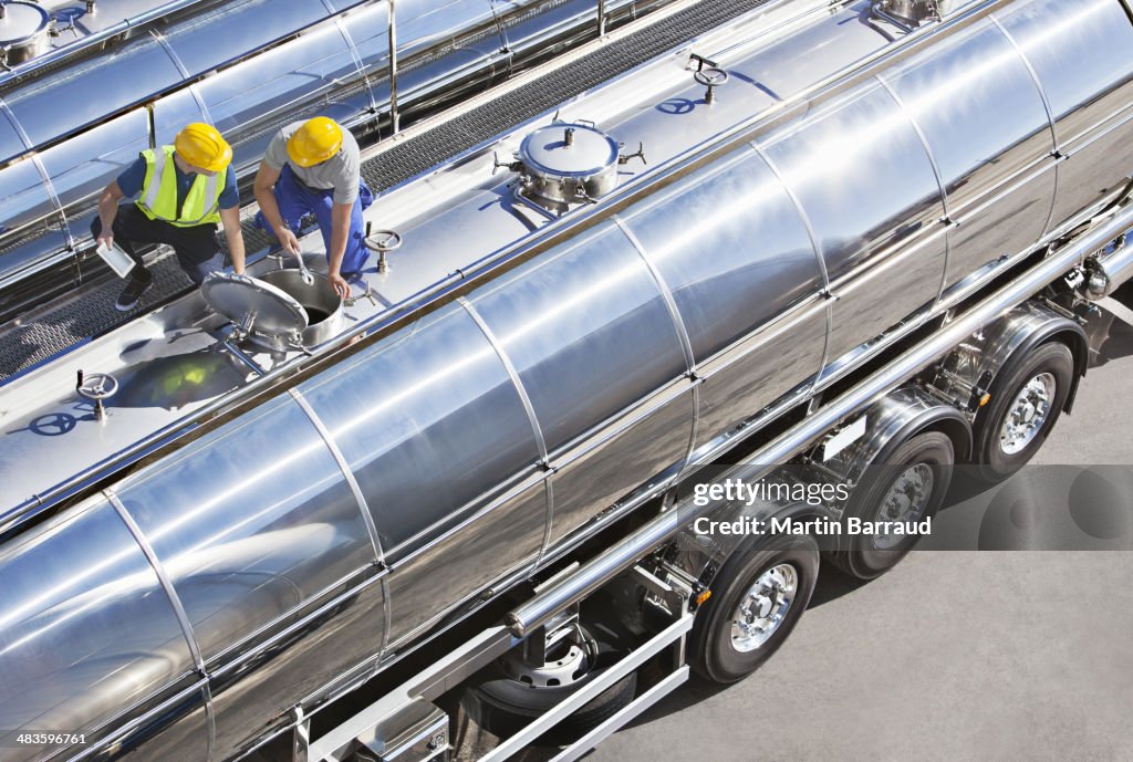 Workers on top of stainless steel milk tanker