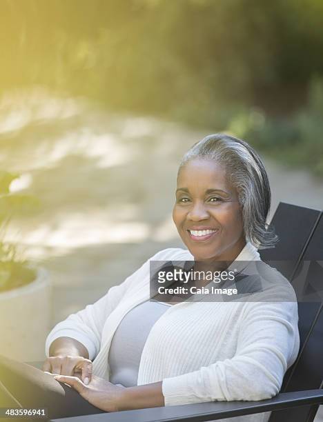 portrait of smiling senior woman outdoors - adirondack chair closeup stock pictures, royalty-free photos & images