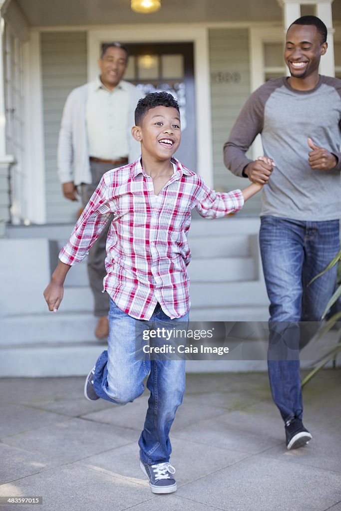 Father and son holding hands and running outside house