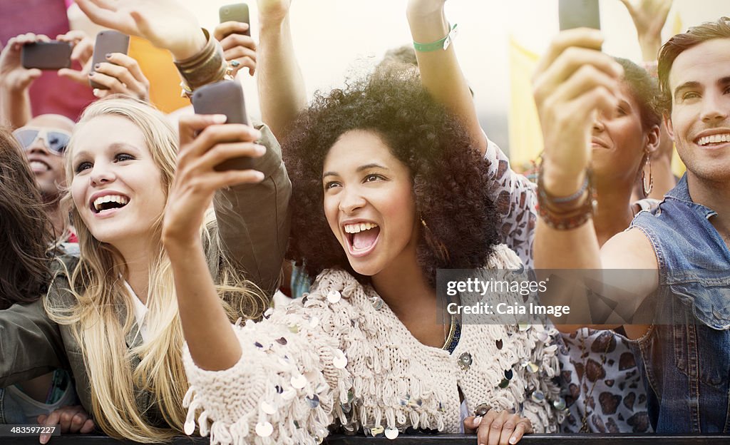 Fãs com câmara para telefones a celebrar no festival de Música