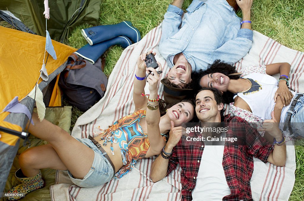 Friends taking self-portrait on blanket outside tent at music festival