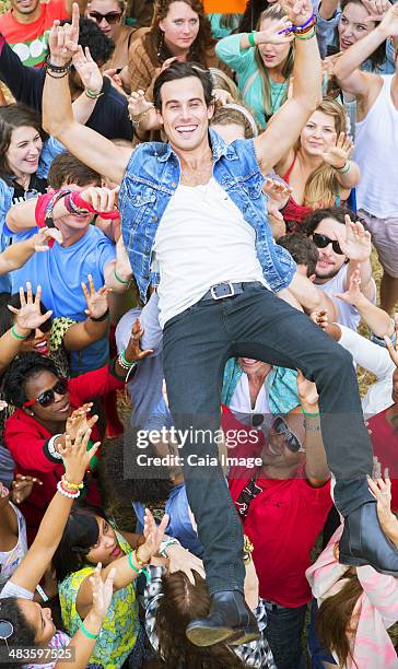 portrait of man crowd surfing at music festival - crowdsurfing stockfoto's en -beelden