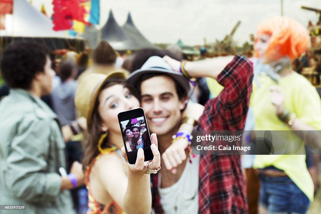 Couple taking self-portrait with camera phone at music festival