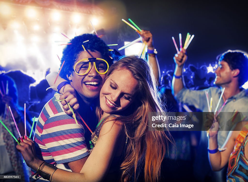 Couple with glow sticks hugging at music festival