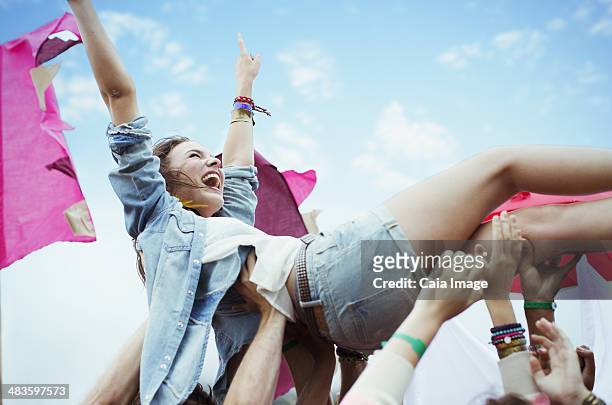 enthusiastic woman crowd surfing at music festival - crowdsurfing stockfoto's en -beelden