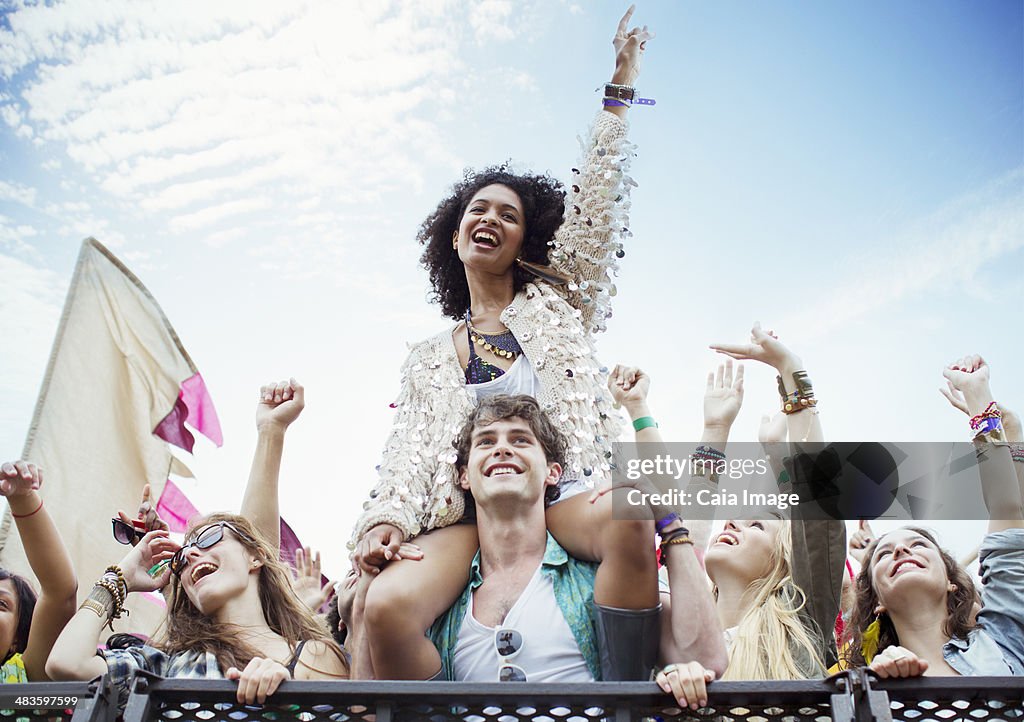 Cheering woman on manês shoulders at music festival