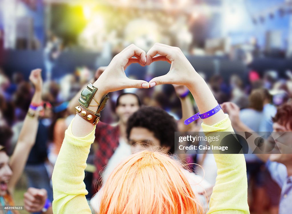 Woman forming heart-shape with hands at music festival