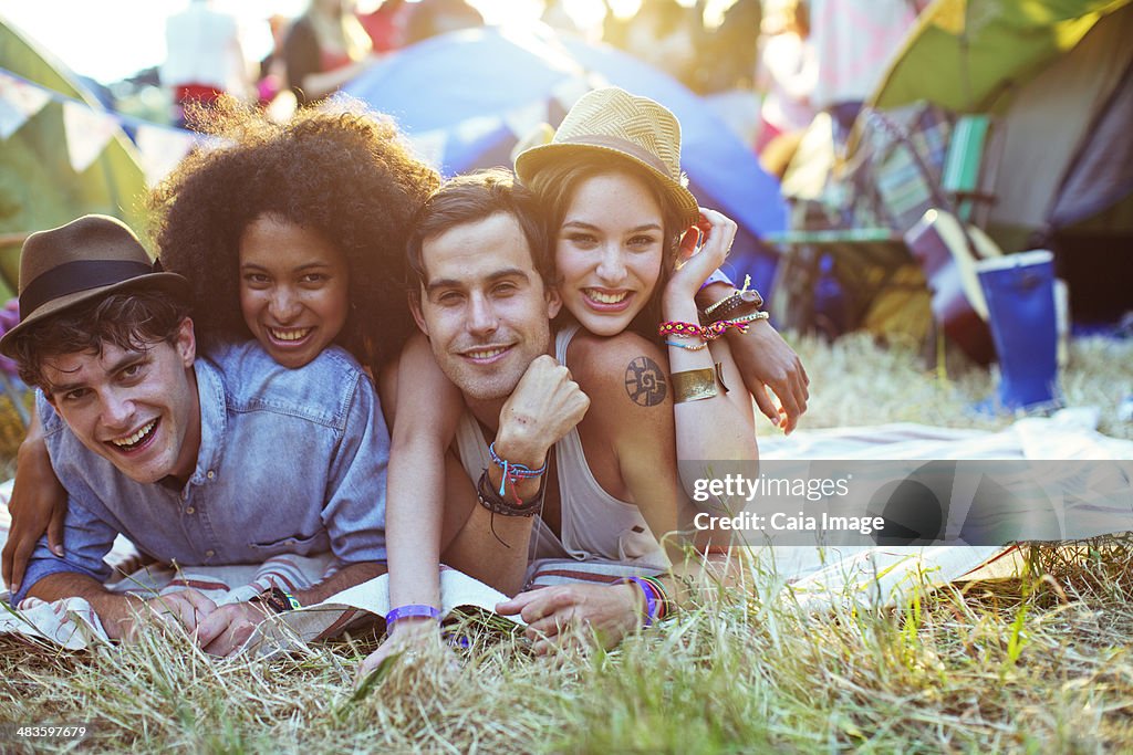 Portrait of friends laying on blanket outside tents at music festival