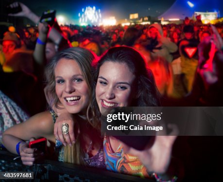 Friends taking self-portrait with camera phone at music festival Friends taking self-portrait with camera phone at music festival